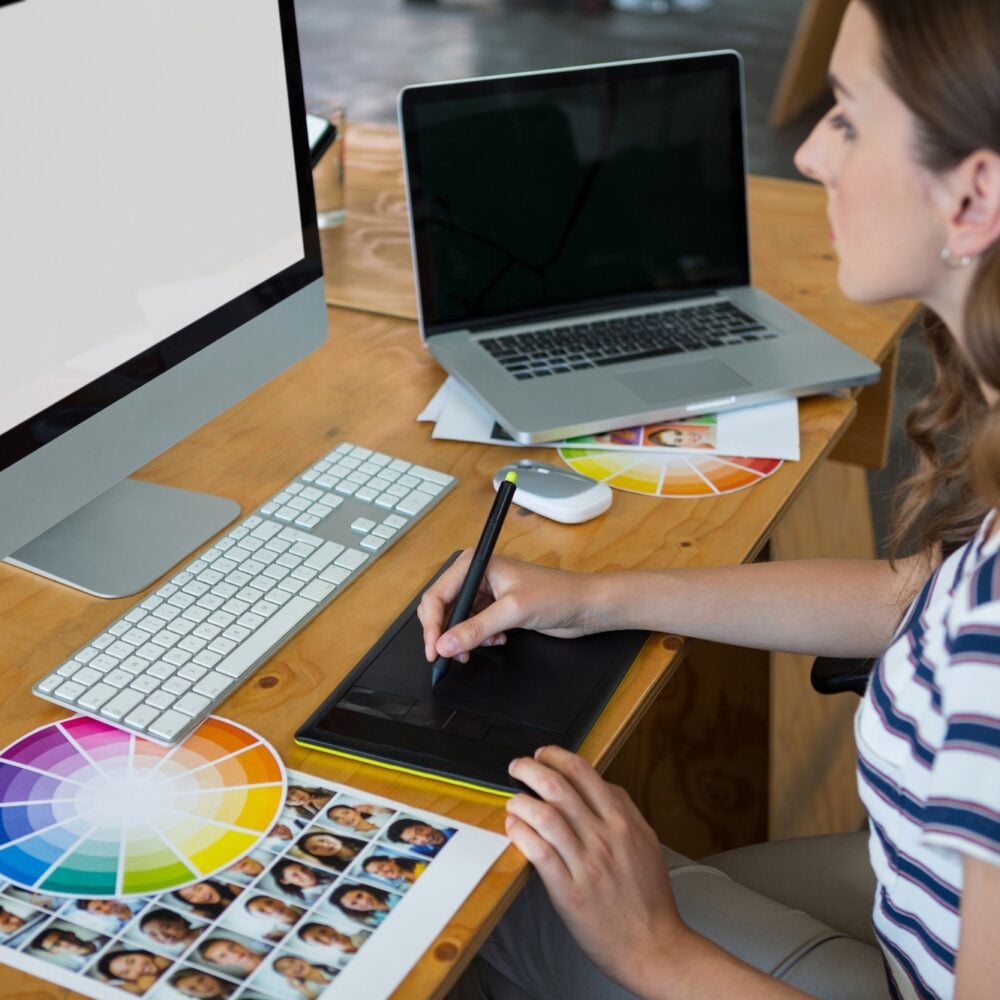 Female graphic designer using graphics tablet at desk